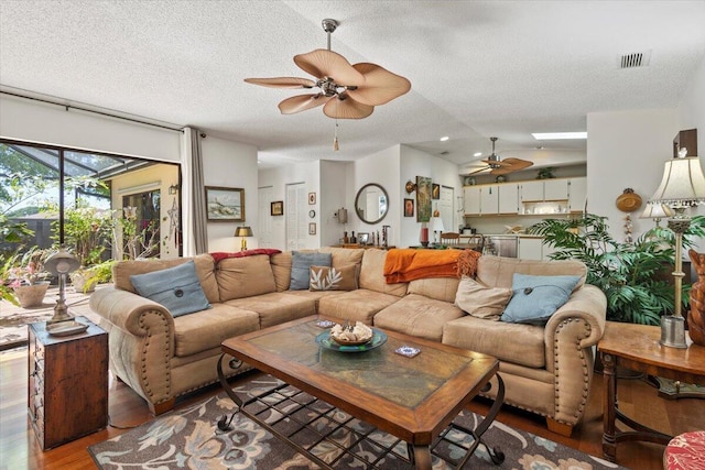 living room with visible vents, light wood-style floors, ceiling fan, a textured ceiling, and vaulted ceiling