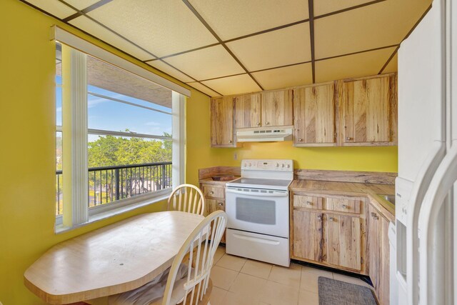 3301 NW 47th Ter Unit 410, Lauderdale Lakes, FL 33319 - kitchen with under cabinet range hood, light tile patterned floors, white appliances, a paneled ceiling, and light countertops