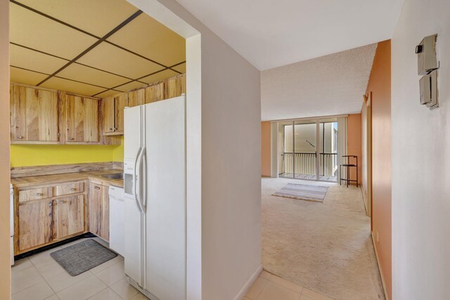 3301 NW 47th Ter Unit 410, Lauderdale Lakes, FL 33319 - kitchen with light tile patterned floors, baseboards, white appliances, light carpet, and light countertops