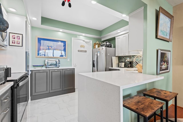 kitchen featuring stainless steel fridge, black electric range oven, marble finish floor, a peninsula, and decorative backsplash