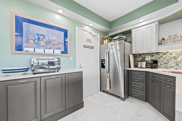 kitchen with light countertops, gray cabinets, and stainless steel fridge with ice dispenser