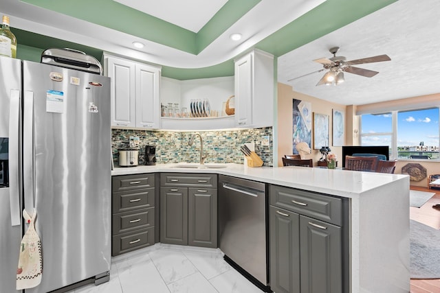 kitchen with a peninsula, appliances with stainless steel finishes, white cabinetry, and a sink