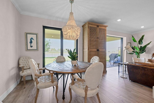 dining room featuring baseboards, ornamental molding, light wood-style flooring, and a notable chandelier
