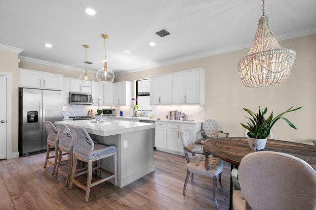 kitchen featuring visible vents, decorative backsplash, a center island, white cabinets, and appliances with stainless steel finishes