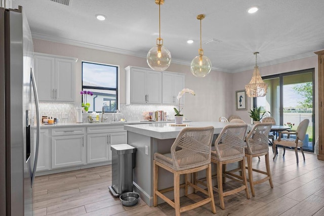 kitchen with light countertops, a kitchen island, a healthy amount of sunlight, and stainless steel fridge with ice dispenser