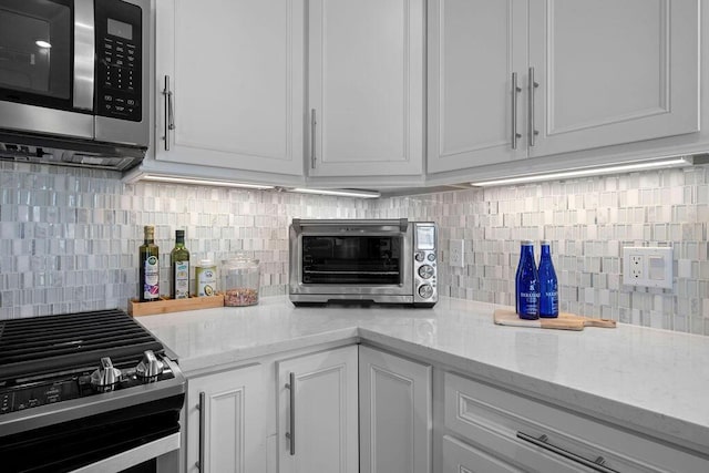 kitchen with a toaster, tasteful backsplash, stainless steel appliances, and white cabinetry