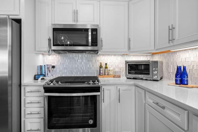 kitchen with a toaster, appliances with stainless steel finishes, white cabinets, and backsplash
