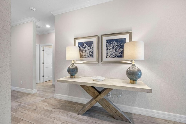 hall featuring crown molding, baseboards, and light wood finished floors