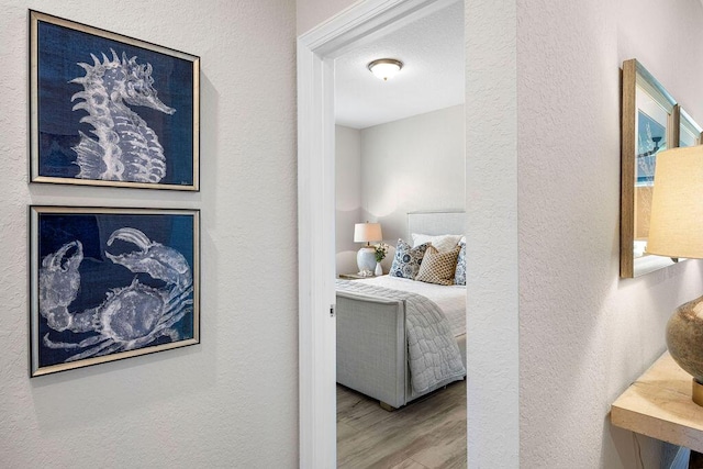 bedroom with a textured wall and wood finished floors
