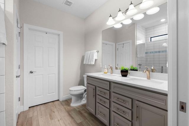 bathroom with double vanity, toilet, visible vents, and a sink