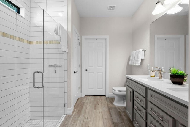 full bathroom with a sink, toilet, wood finished floors, visible vents, and a stall shower