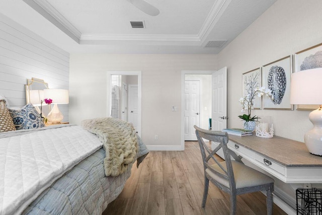 bedroom featuring wood-type flooring, crown molding, visible vents, and a raised ceiling