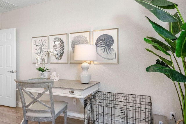 home office with baseboards, visible vents, and wood finished floors