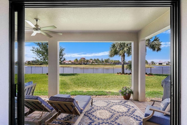 view of patio / terrace with a water view, fence, and ceiling fan