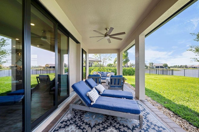 view of patio featuring fence, a water view, and ceiling fan