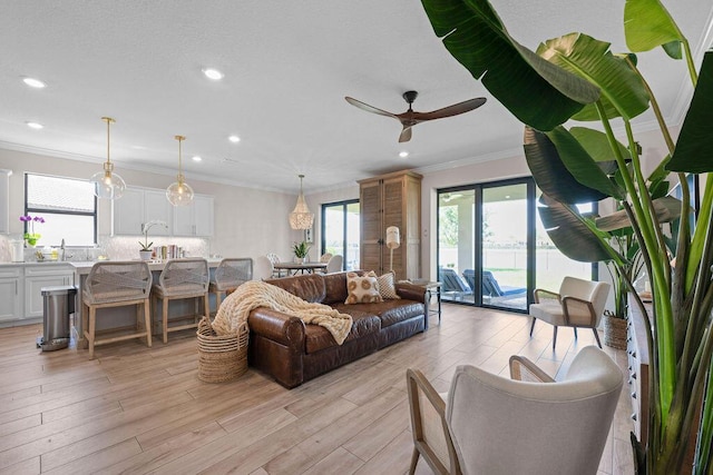 living room featuring crown molding, recessed lighting, ceiling fan, and light wood finished floors