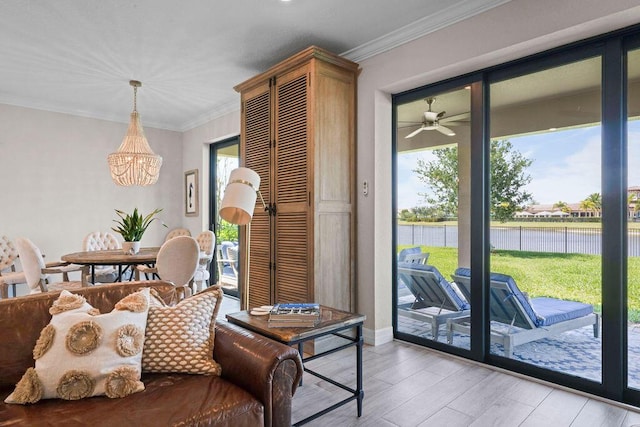 living area with an inviting chandelier, a water view, crown molding, and light wood-type flooring