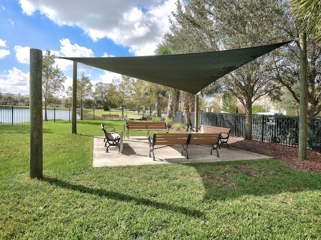 view of home's community with a lawn, a water view, and fence