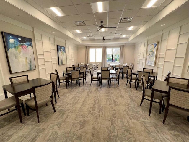carpeted dining space with visible vents, a ceiling fan, a paneled ceiling, and built in features