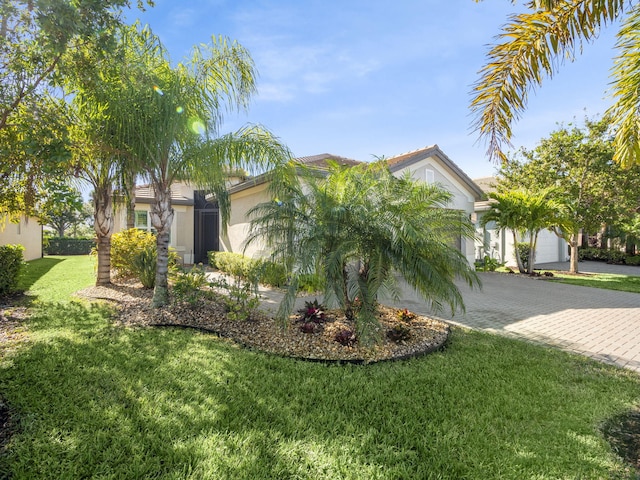 view of front of house featuring a garage, stucco siding, decorative driveway, and a front yard