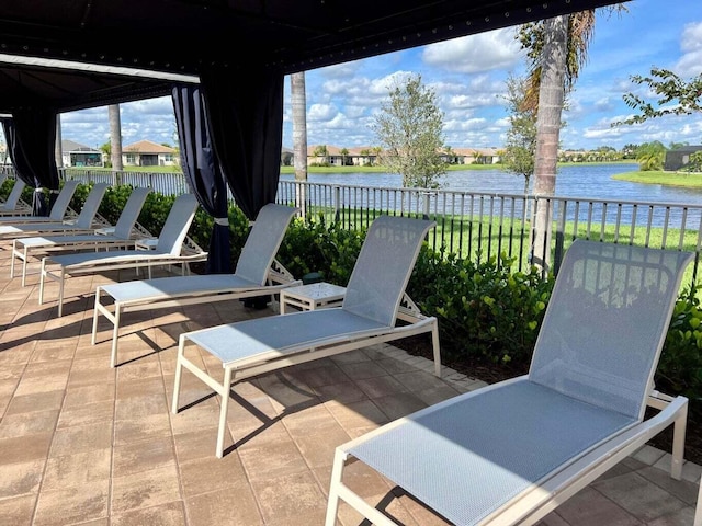 view of patio with a water view and fence
