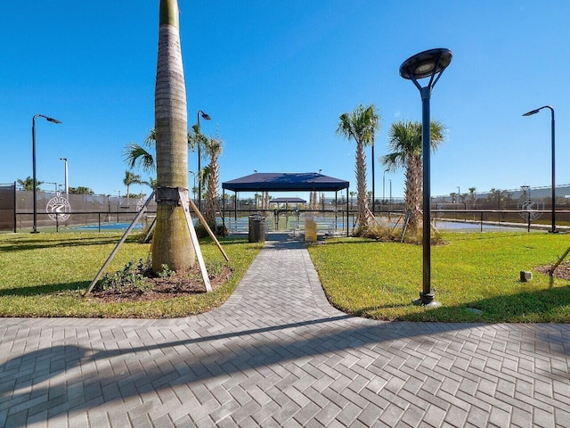 surrounding community featuring a gazebo, a water view, a lawn, and fence