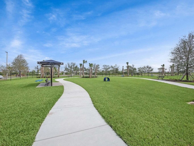 view of property's community featuring a lawn and fence