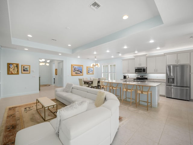 living area featuring visible vents, a raised ceiling, light tile patterned floors, and a chandelier