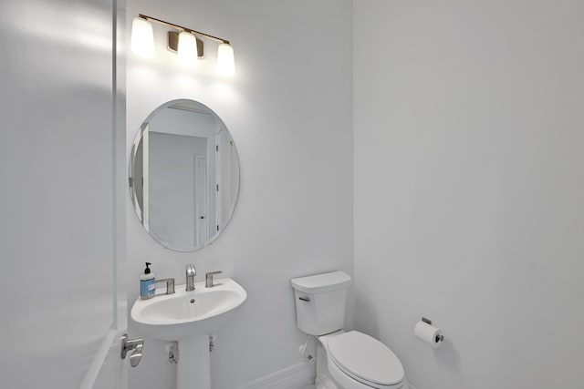 half bath featuring baseboards, a sink, and toilet