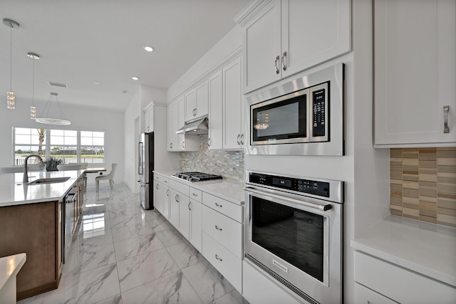 kitchen featuring a sink, marble finish floor, stainless steel appliances, recessed lighting, and tasteful backsplash