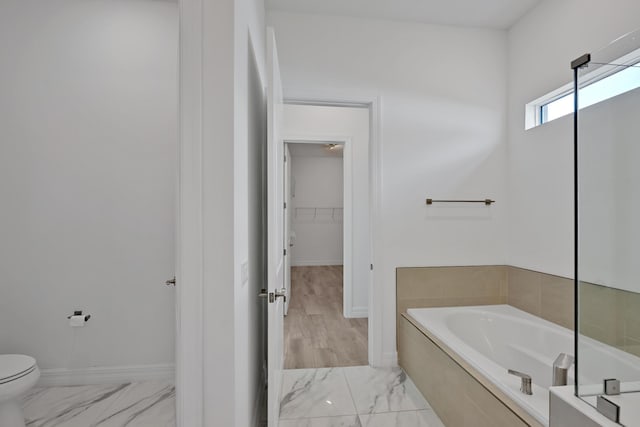 full bath with baseboards, toilet, a bath, and marble finish floor