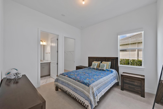 bedroom with baseboards, light colored carpet, and connected bathroom