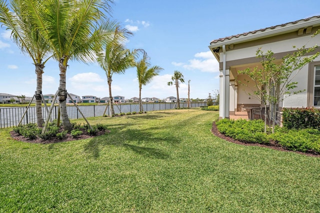 view of yard with a water view, fence, and a residential view