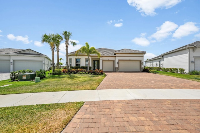 view of front of home featuring a garage, a front lawn, decorative driveway, stucco siding, and a tile roof