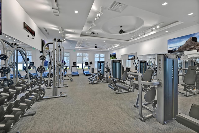 gym featuring carpet flooring, a tray ceiling, visible vents, and ceiling fan