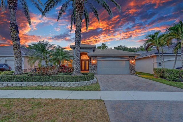 mediterranean / spanish home with driveway, french doors, an attached garage, stucco siding, and stone siding