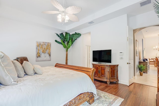 bedroom featuring arched walkways, baseboards, visible vents, and wood finished floors
