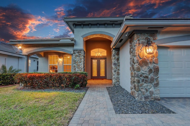 property entrance featuring stone siding, stucco siding, and french doors