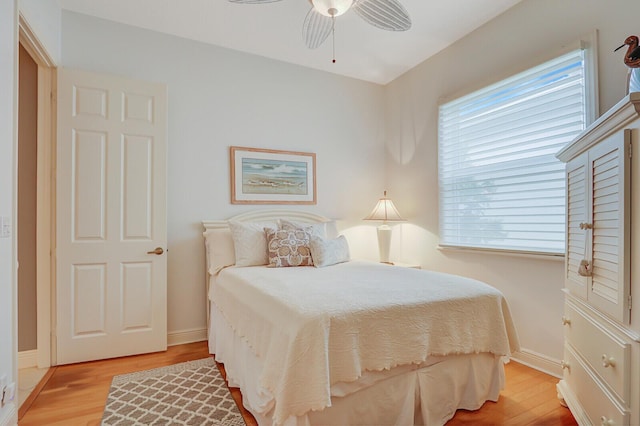 bedroom with light wood finished floors, baseboards, and a ceiling fan