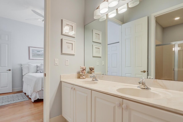bathroom featuring double vanity, wood finished floors, a stall shower, and a sink