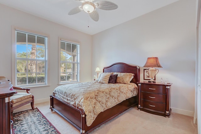 bedroom featuring light colored carpet, baseboards, and ceiling fan