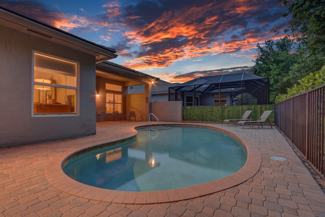 view of swimming pool featuring a patio area, fence, a fenced in pool, and glass enclosure