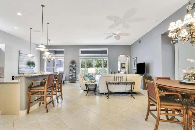 dining space with ceiling fan with notable chandelier, visible vents, recessed lighting, arched walkways, and light tile patterned floors