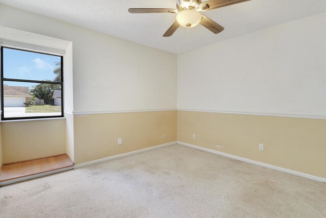 carpeted empty room featuring a ceiling fan and baseboards