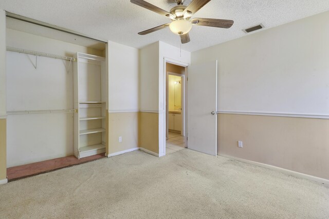 unfurnished bedroom featuring carpet flooring, ceiling fan, a textured ceiling, visible vents, and a closet