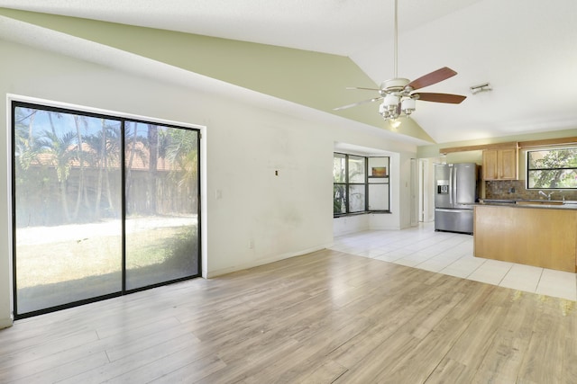 unfurnished living room featuring ceiling fan, visible vents, vaulted ceiling, a sink, and light wood-style flooring