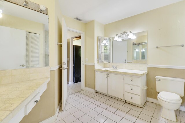 bathroom with vanity, visible vents, toilet, tile patterned floors, and tasteful backsplash