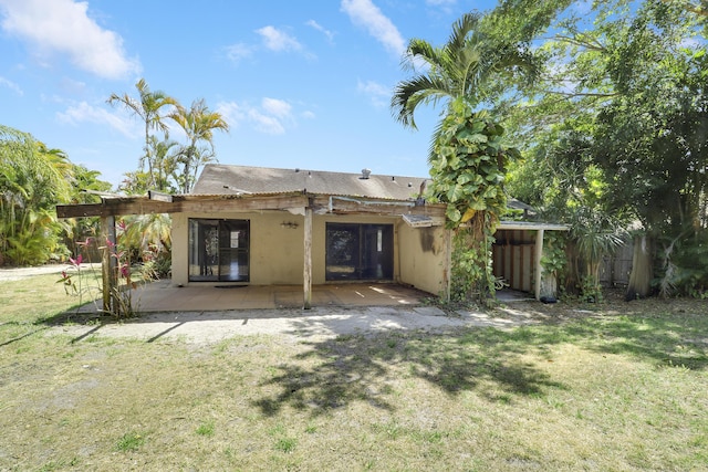 back of property with a yard, a patio, and stucco siding
