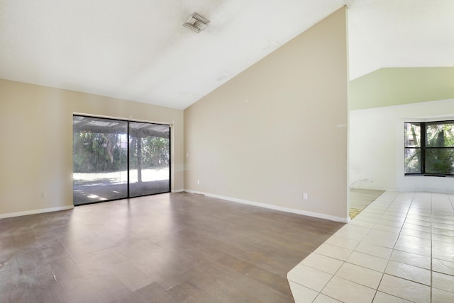 spare room featuring baseboards, vaulted ceiling, and visible vents
