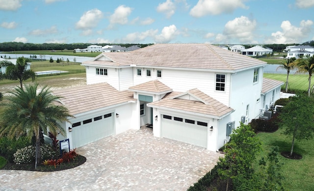 20136 Se Bridgewater Drive Livingston Model, Jupiter, FL 33458 - exterior space with an attached garage, stucco siding, a water view, decorative driveway, and central air condition unit